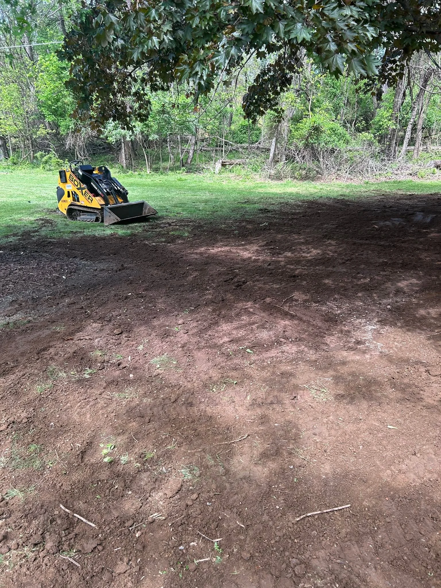 Compact track loader grading and leveling bare soil on cleared residential lot