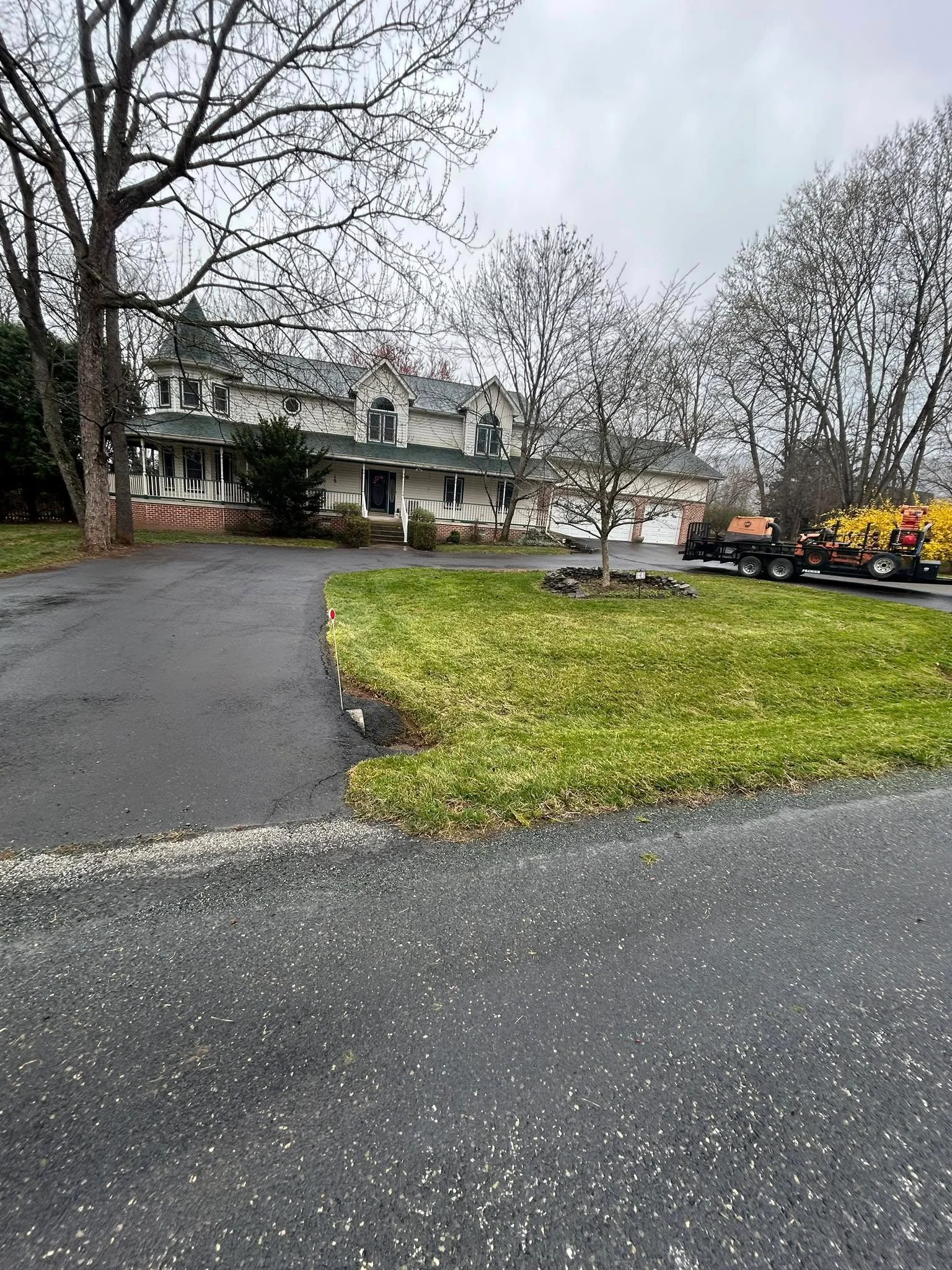 Freshly mowed lawn and maintained driveway at residential colonial home with brick base