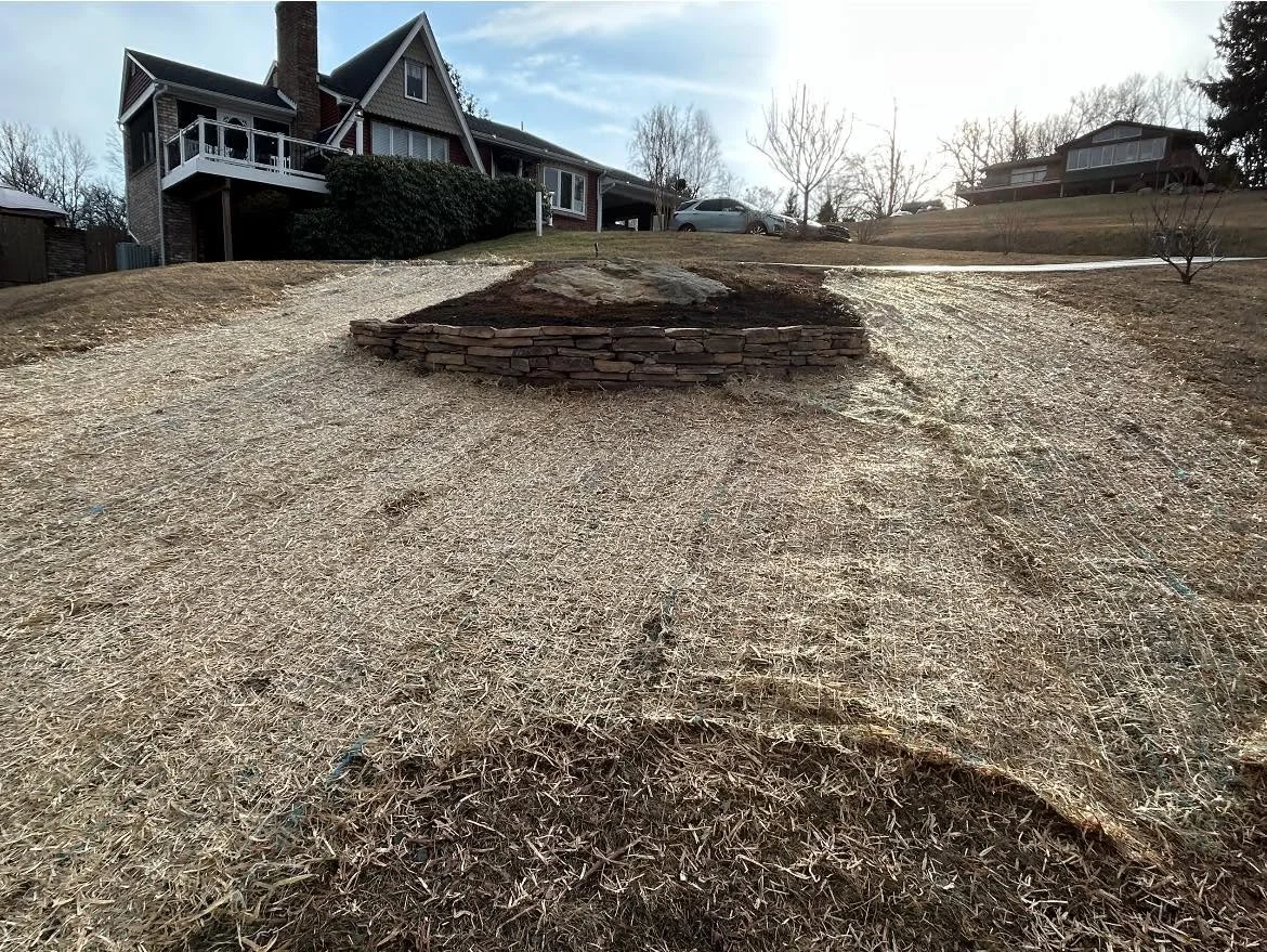 Stone retaining wall with mulch-filled landscape bed and gravel base in residential yard
