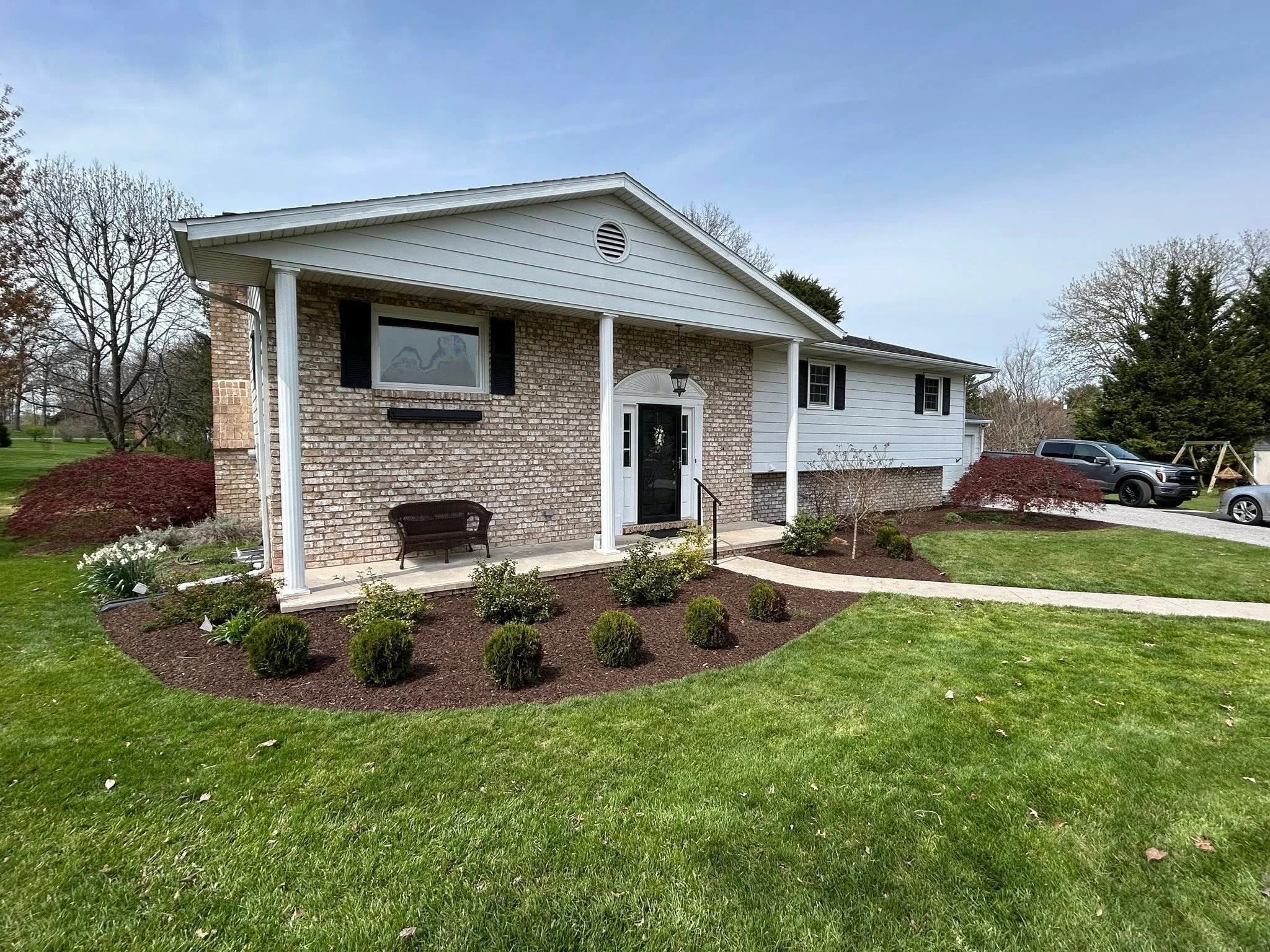 Brick home with newly installed mulch beds, ornamental shrubs, and evergreen plantings around front entrance
