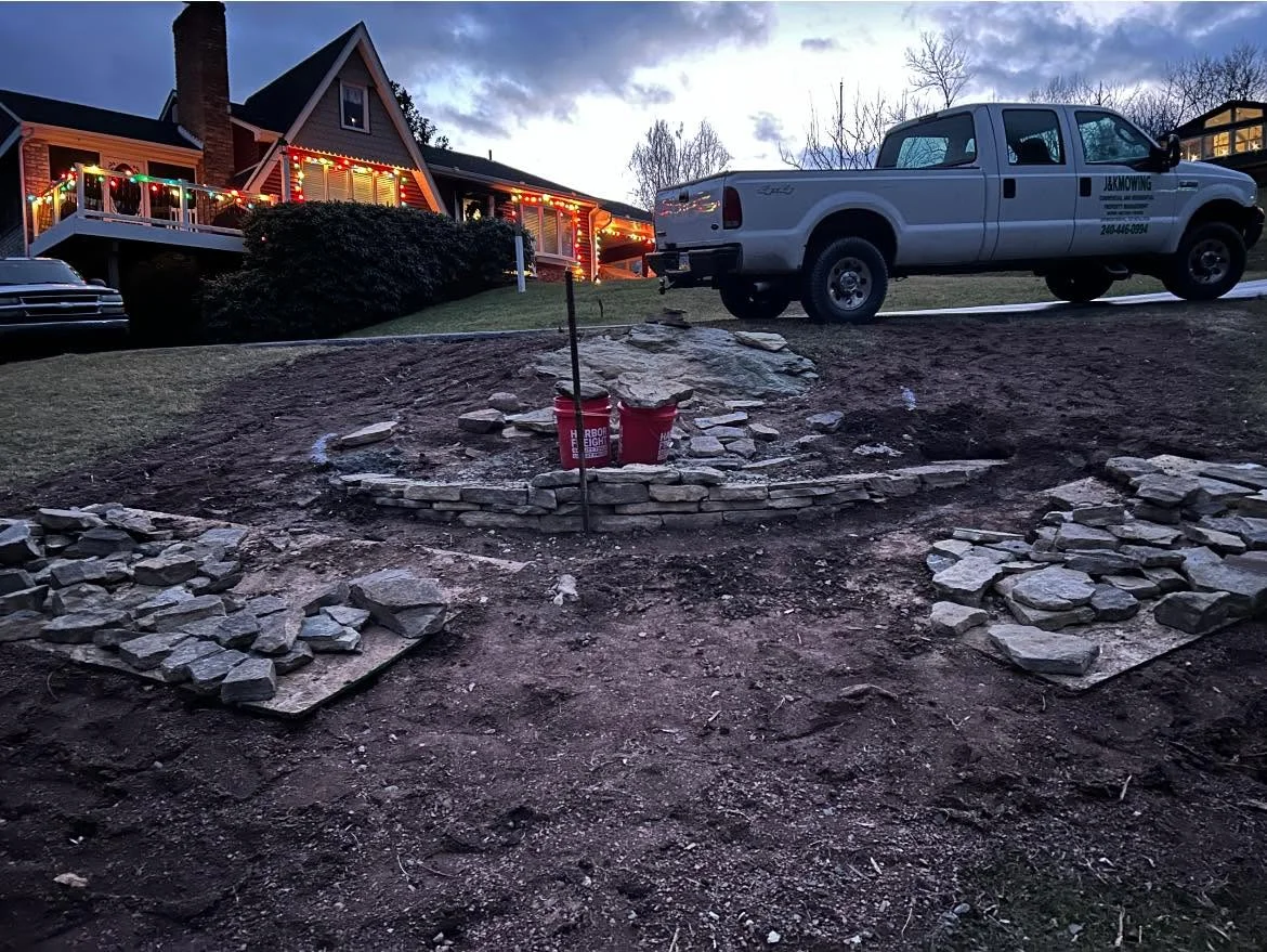 Circular stone fire pit with metal ring surrounded by stacked natural stone pavers in residential yard